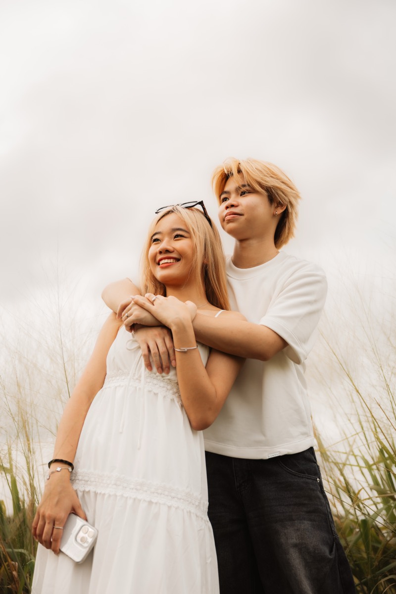 A couple hold each other close, both faces turned to the light.