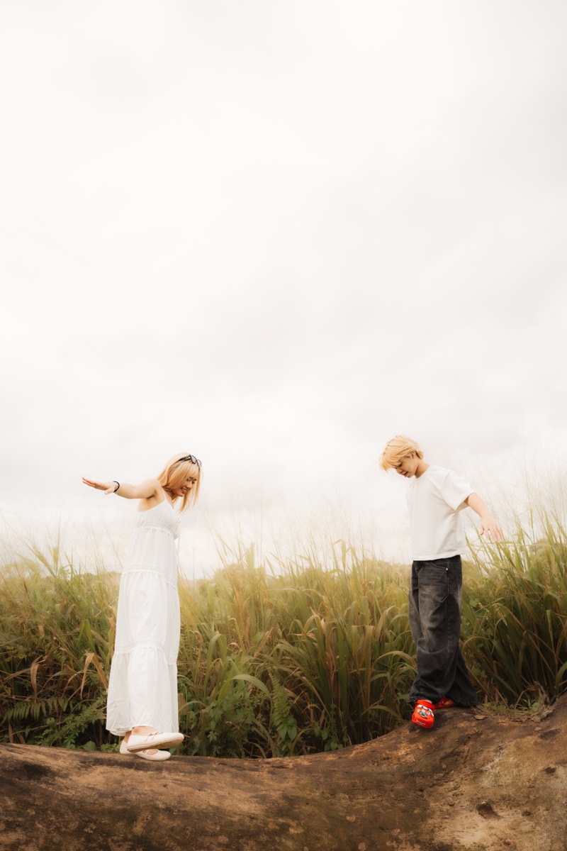 A couple play on a rise, arms outstretched, framed against the sky.
