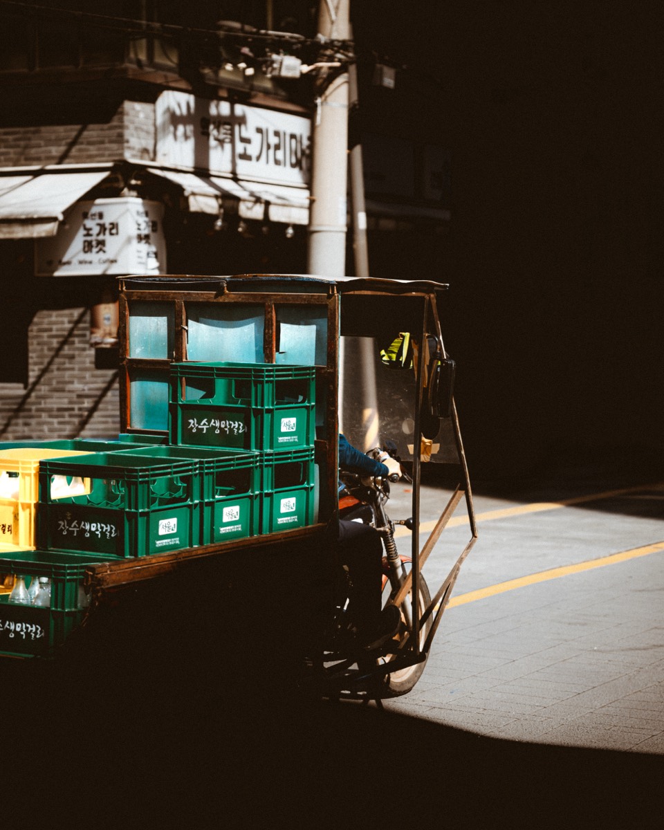 A laden cart of crates sits in a shaft of street light.