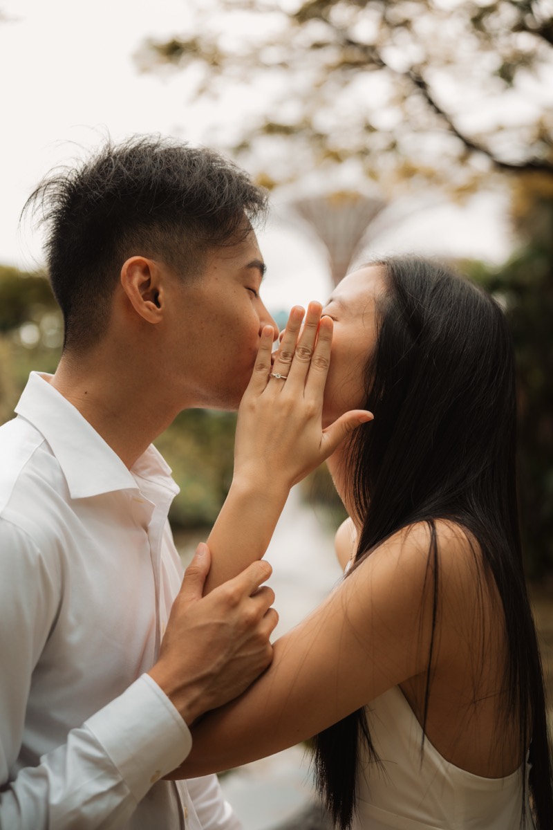 A couple kiss in profile, the Supertrees rising softly out of focus behind them.